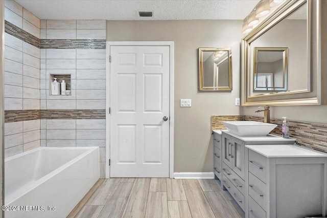 bathroom featuring vanity, a textured ceiling, and a bathtub