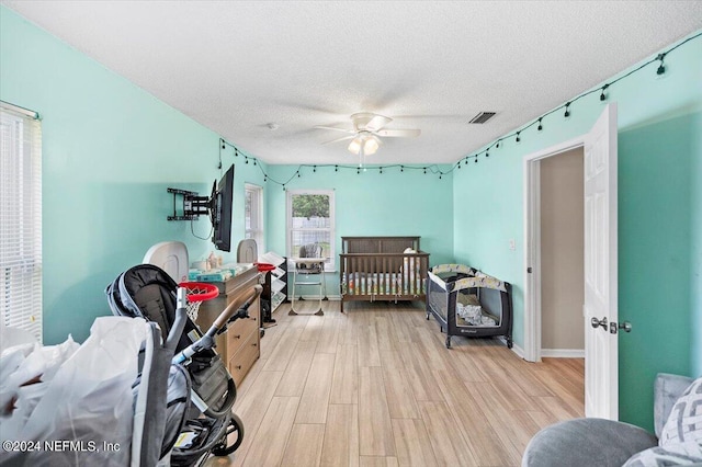 bedroom with ceiling fan, light hardwood / wood-style flooring, and a textured ceiling