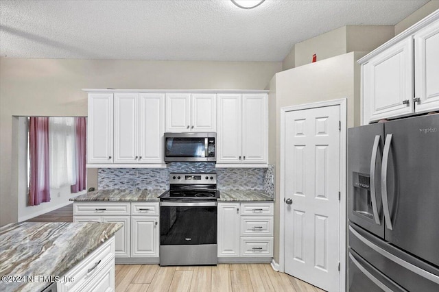 kitchen featuring white cabinets, backsplash, light stone counters, and stainless steel appliances