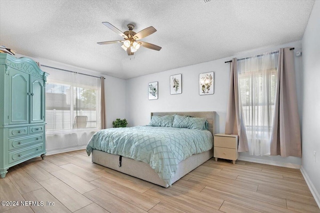 bedroom featuring ceiling fan, a textured ceiling, and light wood-type flooring