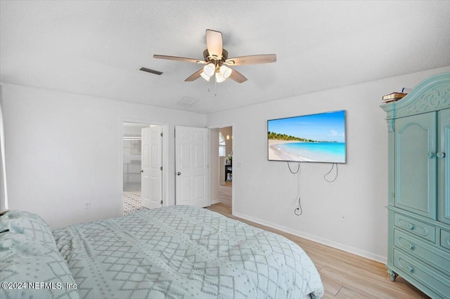 bedroom with ceiling fan, light hardwood / wood-style floors, and a textured ceiling