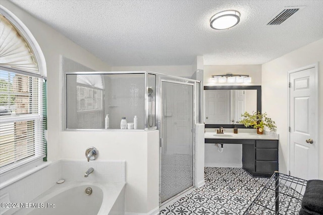 bathroom with tile patterned flooring, shower with separate bathtub, vanity, and a textured ceiling