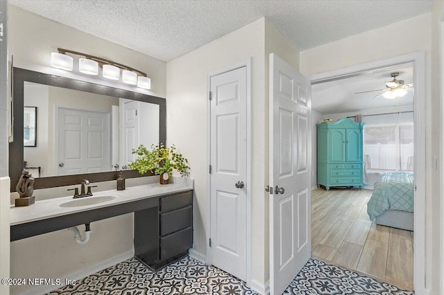 bathroom with a textured ceiling, ceiling fan, wood-type flooring, and sink