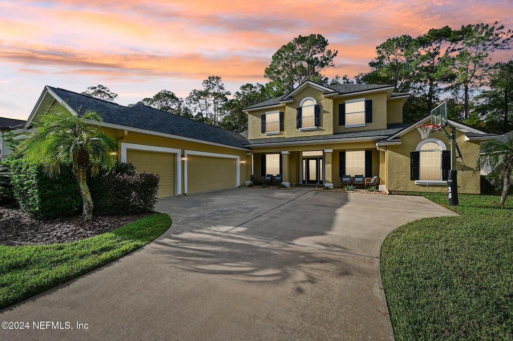 view of front of property with covered porch, a garage, and a lawn