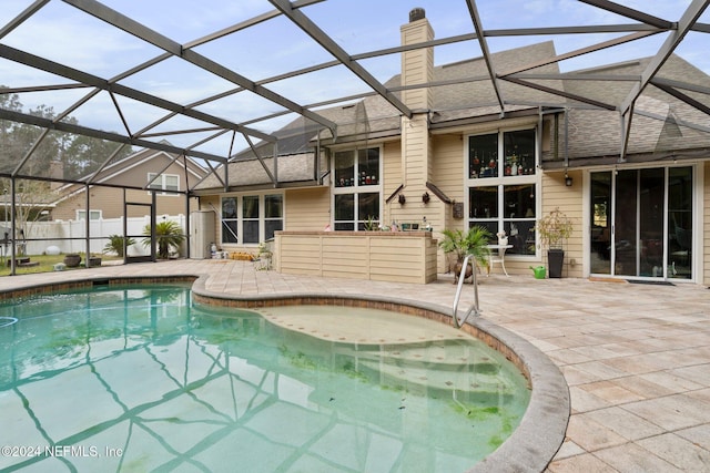 view of swimming pool featuring glass enclosure and a patio