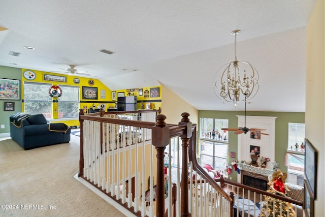 interior space featuring ceiling fan with notable chandelier, carpet floors, a textured ceiling, and vaulted ceiling