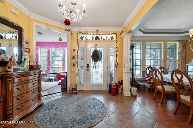 foyer entrance with decorative columns, tile patterned floors, ornamental molding, a textured ceiling, and a chandelier