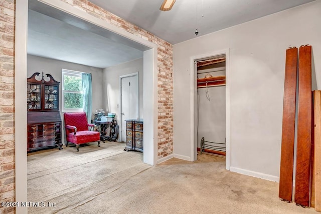 carpeted bedroom featuring a closet, ceiling fan, and brick wall