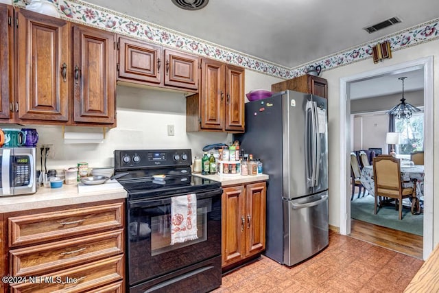 kitchen featuring decorative light fixtures, stainless steel fridge, black range with electric stovetop, and an inviting chandelier