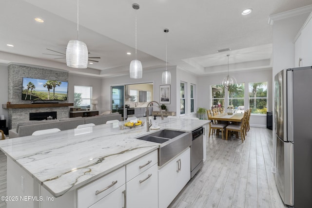 kitchen featuring sink, white cabinetry, appliances with stainless steel finishes, a tray ceiling, and a kitchen island with sink