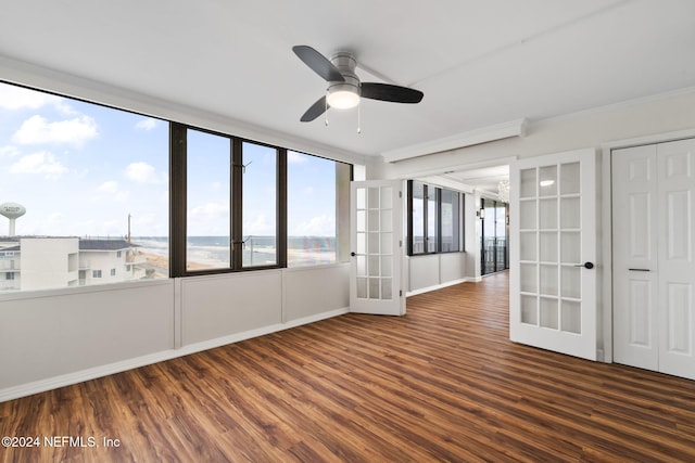 empty room featuring ceiling fan, dark hardwood / wood-style flooring, a water view, and french doors