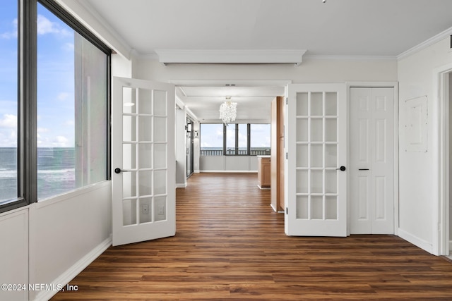 spare room featuring dark hardwood / wood-style flooring, french doors, crown molding, and an inviting chandelier