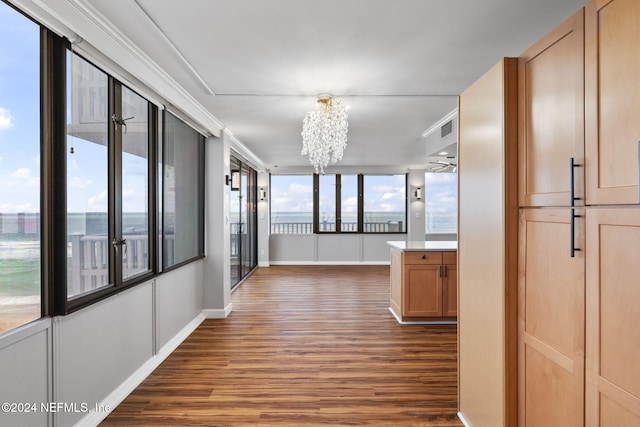 corridor with ornamental molding, dark hardwood / wood-style floors, and an inviting chandelier