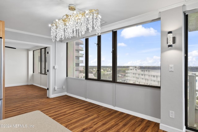 interior space with a wealth of natural light, crown molding, wood-type flooring, and an inviting chandelier