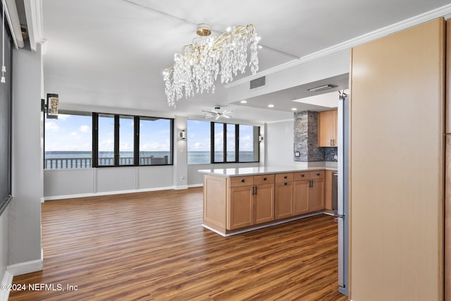 kitchen featuring ceiling fan with notable chandelier, a water view, crown molding, tasteful backsplash, and kitchen peninsula