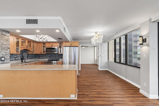 kitchen featuring appliances with stainless steel finishes, tasteful backsplash, crown molding, sink, and a chandelier