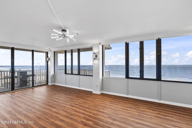 empty room with a notable chandelier, dark hardwood / wood-style flooring, and a water view