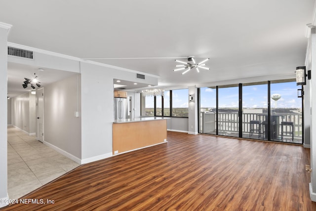 unfurnished living room with ceiling fan, crown molding, expansive windows, and light wood-type flooring