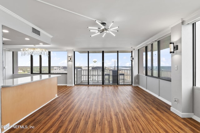 empty room featuring ceiling fan with notable chandelier, dark hardwood / wood-style flooring, plenty of natural light, and crown molding