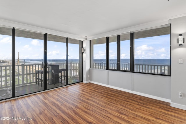 empty room with a water view, a healthy amount of sunlight, and hardwood / wood-style flooring