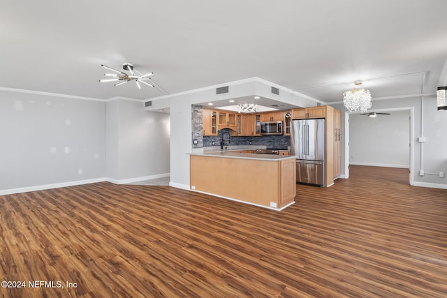 kitchen with kitchen peninsula, dark hardwood / wood-style flooring, backsplash, stainless steel appliances, and an inviting chandelier