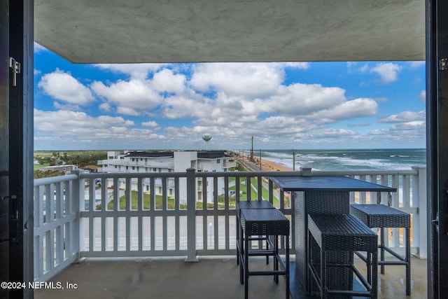 balcony with a water view and a view of the beach