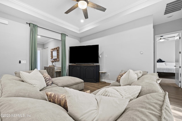 living room featuring a raised ceiling, ceiling fan, dark hardwood / wood-style flooring, and crown molding