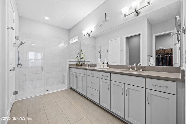 bathroom featuring a textured ceiling, vanity, and walk in shower