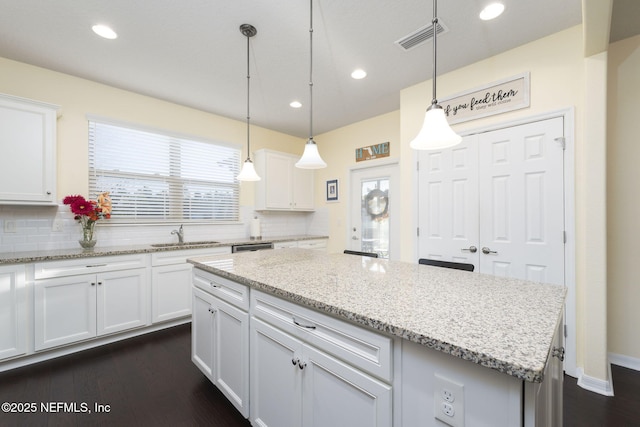 kitchen with decorative light fixtures, a kitchen island, and white cabinetry