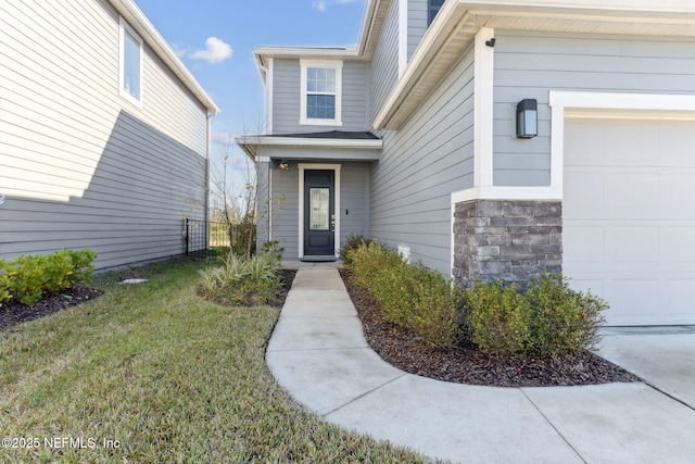 entrance to property featuring a lawn and a garage