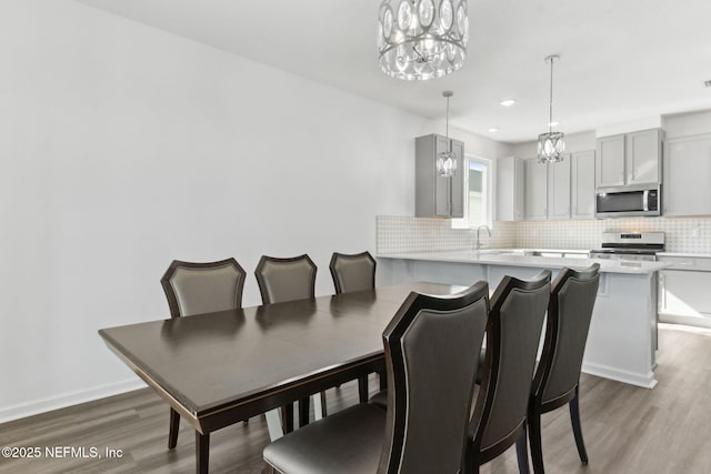 dining space with wood-type flooring, a notable chandelier, and sink