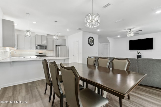 dining space with light hardwood / wood-style floors, ceiling fan, and sink