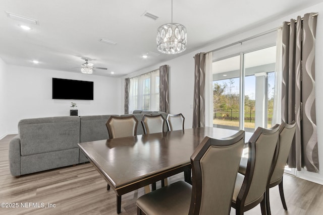 dining room featuring ceiling fan with notable chandelier and light hardwood / wood-style floors