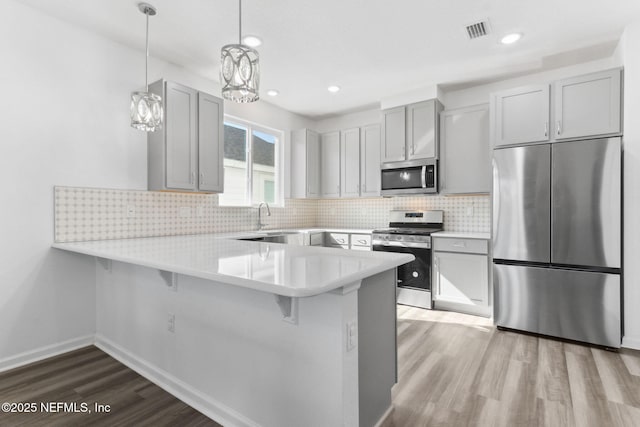 kitchen with decorative light fixtures, a kitchen breakfast bar, kitchen peninsula, and appliances with stainless steel finishes