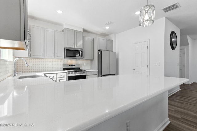 kitchen with kitchen peninsula, backsplash, stainless steel appliances, sink, and pendant lighting