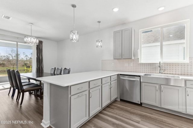 kitchen featuring sink, hanging light fixtures, stainless steel dishwasher, kitchen peninsula, and decorative backsplash