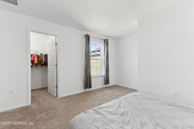 bedroom with light colored carpet, a walk in closet, and a closet