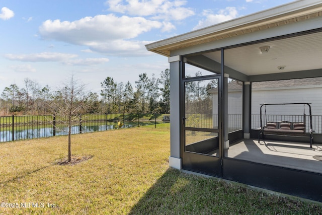 view of yard featuring a sunroom and a water view