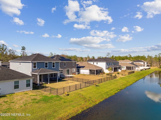 rear view of house with a water view and a lawn