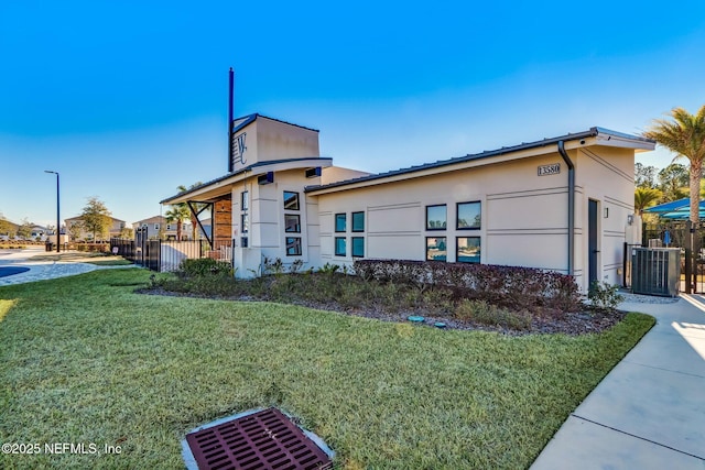 view of side of home with a lawn and central AC