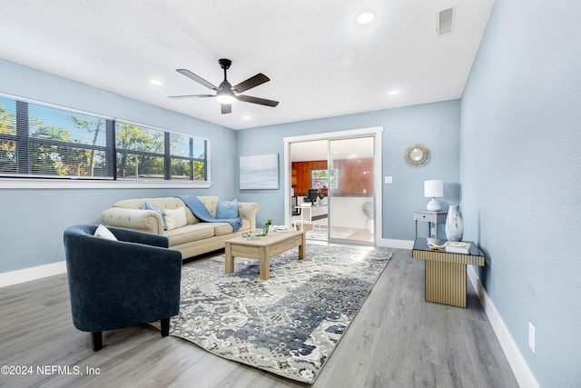 living room with wood-type flooring, a textured ceiling, ceiling fan, and a healthy amount of sunlight