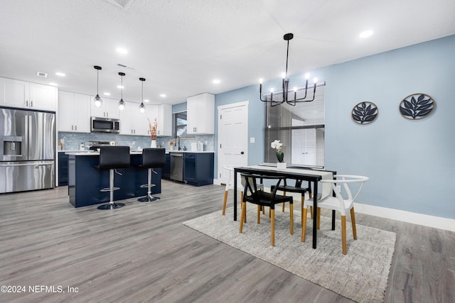 dining area with sink, an inviting chandelier, and light wood-type flooring