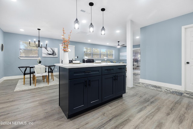 kitchen with ceiling fan with notable chandelier, a center island, hanging light fixtures, and light hardwood / wood-style flooring