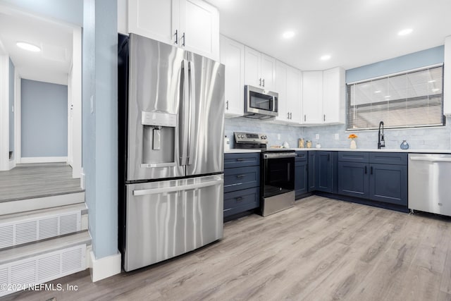 kitchen with stainless steel appliances, blue cabinets, sink, white cabinets, and light hardwood / wood-style floors