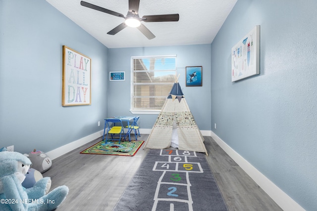 game room with a textured ceiling, dark hardwood / wood-style floors, and ceiling fan