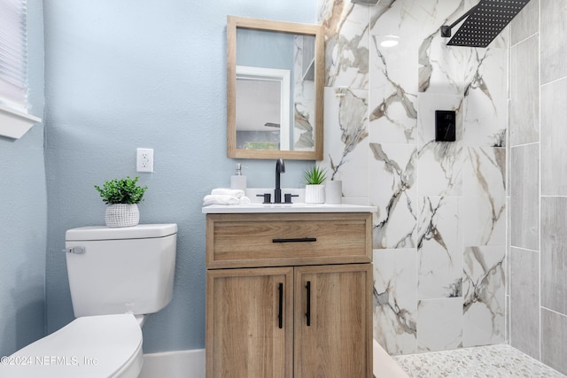 bathroom featuring toilet, vanity, and tiled shower