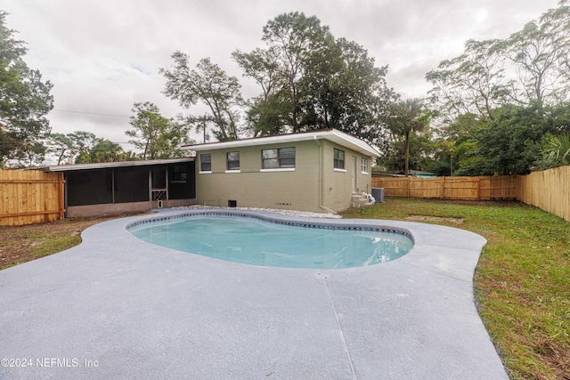 view of swimming pool with a sunroom and a yard