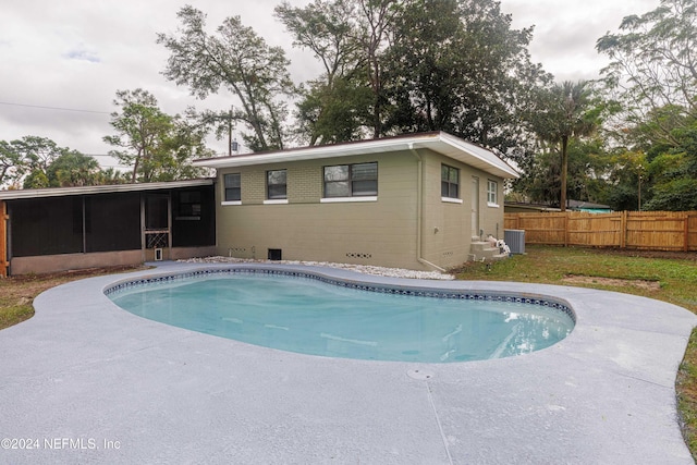 view of swimming pool with central AC unit and a sunroom