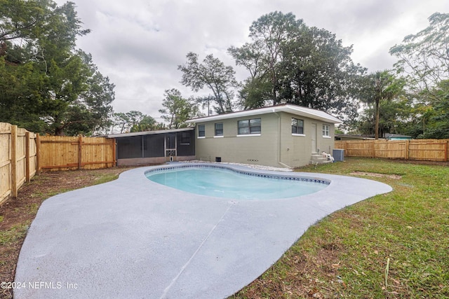 view of swimming pool featuring a sunroom, a yard, and central AC unit