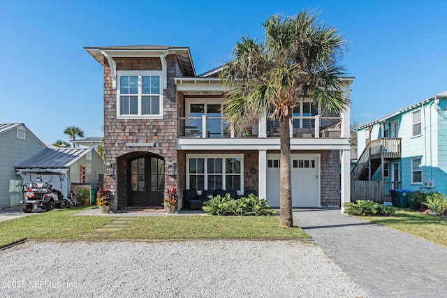 view of front of home featuring a garage, a balcony, a front yard, and french doors